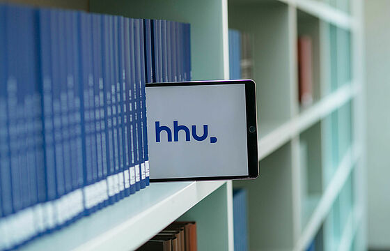 Tablet mit Anzeige "HHU", Bücherregal